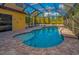 Inviting screened-in pool area featuring a sparkling pool and brick-paved patio for relaxation and entertainment at 11645 Belle Haven Dr, New Port Richey, FL 34654