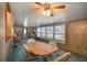 Dining area adjacent to living space, wood panel walls, ceiling fan and windows at 3844 Kim Dr, Wesley Chapel, FL 33543