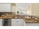 Granite kitchen countertops with a double sink, dishwasher, and view to the living area at 4516 Seagull Dr # 805, New Port Richey, FL 34652