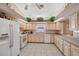 Bright kitchen featuring light wood cabinetry, white appliances, and tile floors at 714 Charlotte Ave, Tarpon Springs, FL 34689
