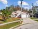Elevated view of a single-story home with a landscaped front yard, palm trees, and a two-car garage at 7717 Foxbear Ct, New Port Richey, FL 34655