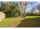 Spacious, fenced backyard with lush green lawn and mature trees at 7717 Foxbear Ct, New Port Richey, FL 34655