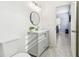 Bright bathroom with gray vanity, round mirror, and view to adjacent bedroom at 7717 Foxbear Ct, New Port Richey, FL 34655