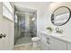 Modern bathroom with a glass shower, white vanity, and a round mirror at 7717 Foxbear Ct, New Port Richey, FL 34655