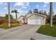 One-story home with two-car garage, driveway, palm trees, and fenced yard at 7717 Foxbear Ct, New Port Richey, FL 34655
