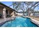 Relaxing screened-in pool area with custom pool and patio furniture and beautiful, mature landscaping at 692 Challice Dr, Spring Hill, FL 34609