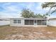 Rear view of house showcasing a screened patio and landscaping at 9240 Whitman Ln, Port Richey, FL 34668