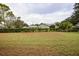View of a grassy backyard with hedges and houses in the background at 9327 Whitstone Ct, New Port Richey, FL 34655