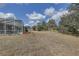 Expansive backyard featuring a screened-in pool area, lush trees, and open space at 9376 Bearwalk Path, Weeki Wachee, FL 34613