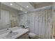 Well-lit bathroom features a single vanity, toilet, and shower with a decorative curtain at 9376 Bearwalk Path, Weeki Wachee, FL 34613