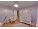 Charming purple bedroom with a white crib, rocking chair, and decorative wall art at 9376 Bearwalk Path, Weeki Wachee, FL 34613