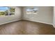 Bright bedroom with wood-look flooring and two windows overlooking the lush green landscape at 106 Aurora E St, Venice, FL 34285