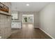 Open-concept living room with brick accent wall, wood-look flooring and view into the kitchen at 106 Aurora E St, Venice, FL 34285