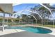 A beautiful screened-in pool surrounded by lush landscaping and tropical palm trees at 18242 Autumn Lake Blvd, Hudson, FL 34667