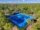 Two tennis courts with blue surface and surrounding trees at 3337 Autumn Amber Dr, Spring Hill, FL 34609