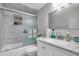 Bright bathroom features a shower with marble-tile surround and a white vanity with quartz countertop at 3337 Darlington Rd, Holiday, FL 34691