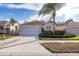 Tan house with a two car garage and palm tree at 390 Royal Palm Way, Spring Hill, FL 34608