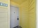 Condo building entry with a white door and yellow siding at 455 Alt 19 S # 163, Palm Harbor, FL 34683