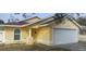 House exterior featuring a yellow stucco exterior, attached garage, and mature landscaping at 5031 6Th N Ave, St Petersburg, FL 33710
