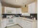 Well-lit kitchen with white appliances and cabinetry, backsplash and light tile floors at 14120 Whitecap Ave, Hudson, FL 34667