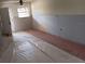 Living room space with new drywall installed, and an exterior door with tile floor beneath plastic sheeting at 4829 Onyx Ln # 102, New Port Richey, FL 34652