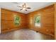 Bedroom featuring two windows with natural light, wood paneled walls, and ceiling fan at 6051 Valley Spring Dr, Brooksville, FL 34601