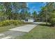 Exterior view of a home featuring a long driveway and a detached carport, surrounded by mature trees at 11085 Stilt Ave, Brooksville, FL 34614