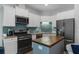 This is a well-lit kitchen with white cabinets, stainless steel appliances, blue backsplash and a wooden island at 11085 Stilt Ave, Brooksville, FL 34614