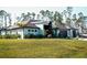 A modern home with dark roof, wood accents and a lush green lawn surrounded by tall trees at 12149 Chapman Ave, Port Charlotte, FL 33953