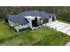 Aerial view of a modern home with dark roof, lush lawn, and a two-car garage at 12149 Chapman Ave, Port Charlotte, FL 33953