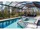 Covered pool and hot tub area with outdoor seating, lounge chairs and an umbrella, surrounded by trees at 12149 Chapman Ave, Port Charlotte, FL 33953