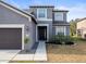 Close-up of a gray two-story home featuring an attached garage and trimmed front yard at 14143 Wake Robin Dr, Brooksville, FL 34604