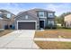 Two-story home features a gray exterior, attached garage, and well-manicured front lawn at 14143 Wake Robin Dr, Brooksville, FL 34604