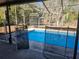 Inviting screened-in pool area features a bright blue pool, surrounding trees, and protective fencing at 6141 Freeport Dr, Spring Hill, FL 34606