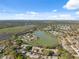 Aerial view showcasing the neighborhood's peaceful homes surrounding a scenic pond under a partly cloudy blue sky at 7414 Heather Walk Dr, Weeki Wachee, FL 34613