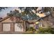 Charming single-story home with a brick driveway, two-car garage, mature trees, and well-lit entry at 7414 Heather Walk Dr, Weeki Wachee, FL 34613