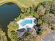 Aerial view of a community pool area with mature landscaping near a peaceful lake at 7414 Heather Walk Dr, Weeki Wachee, FL 34613