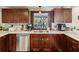 Kitchen area featuring dark wood cabinetry and a stainless steel dishwasher at 7815 Tanglewood Dr, New Port Richey, FL 34654