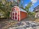 Red shed with white trim and double doors on a gravel and concrete pad at 7815 Tanglewood Dr, New Port Richey, FL 34654