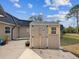 Tan shed with double doors and yellow-shuttered window on a concrete pad against house under blue skies at 7815 Tanglewood Dr, New Port Richey, FL 34654