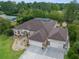 Aerial view of tan-colored home with a screen enclosed pool, manicured lawn, mature trees and a three car garage at 10124 Southern Breeze Ct, Weeki Wachee, FL 34613