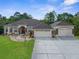 A well-manicured lawn and shrubs accent this spacious, tan home with a three-car garage and decorative stone accents at 10124 Southern Breeze Ct, Weeki Wachee, FL 34613