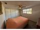 This bright bedroom has a ceiling fan, closet, a bed covered with an orange sheet, and natural light at 6422 Tralee Ave, New Port Richey, FL 34653