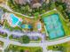 Aerial view of community amenities including a pool, tennis courts, pickleball, parking, and beautiful lush natural landscaping at 8148 Ambersweet Pl, Land O Lakes, FL 34637