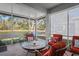 Relaxing screened porch featuring red patio furniture, a round table, and scenic waterfront views at 11243 Merganser Way, New Port Richey, FL 34654