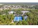 An elevated view of tennis courts, a swimming pool, RV parking, and local houses in a beautiful green surrounding at 13793 Dunwoody Dr, Spring Hill, FL 34609