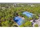 Aerial view of blue tennis and basketball courts, lined with trees, and several parked vehicles nearby at 13793 Dunwoody Dr, Spring Hill, FL 34609