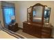 Bedroom with a large, traditional wood dresser and mirror, complemented by a bedside table and window at 12529 Shadow Ridge Blvd, Hudson, FL 34669