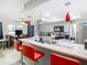 Bright kitchen featuring a breakfast bar with red seating, grey cabinetry, modern appliances and stylish pendant lighting at 12529 Shadow Ridge Blvd, Hudson, FL 34669