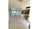 Bright living room featuring neutral tile flooring, large windows, and adjacent kitchen at 4515 Marine Pkwy # 102, New Port Richey, FL 34652